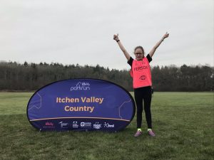 Keira from Winchester Goalball Club stood next to an 'Itchen Valley Country' parkrun banner