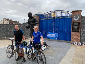 Phil and Kathryn stood, with their bikes, in front of a statue by the main gates at Goodison Park