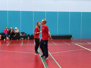 Imogen in the centre of the goalball court at the beginning of a game, shaking hands with her co-official