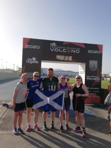 Paul with Scottish teammates proudly holding St. Andrews flag on the finish line of a triathlon
