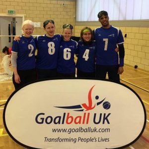 Warren and the rest of the Cambridge team stood together in front of a Goalball UK banner.