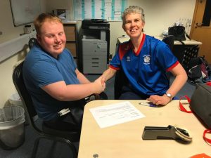 Image shows Ben signing for South Yorkshire Goalball Club. He is pictured shaking hands with Kathryn Fielding following him signing for the club.