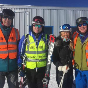 4 skiers wearing hi-vis partially sighted vests ly impi