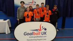 NCW team photo - players and coaches stood behind a Goalball UK banner with medals around their necks