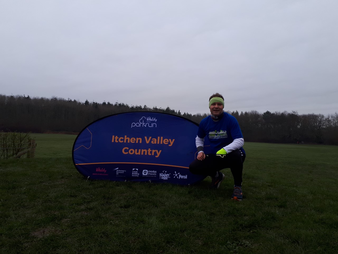 Image shows Tom Evison squatting down next to an Itchen Valley Country banner following a Parkrun