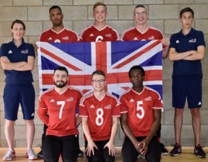 GB Men's squad photo, with coaches Faye and Alex standing either side of the squad who are holding the Union Flag