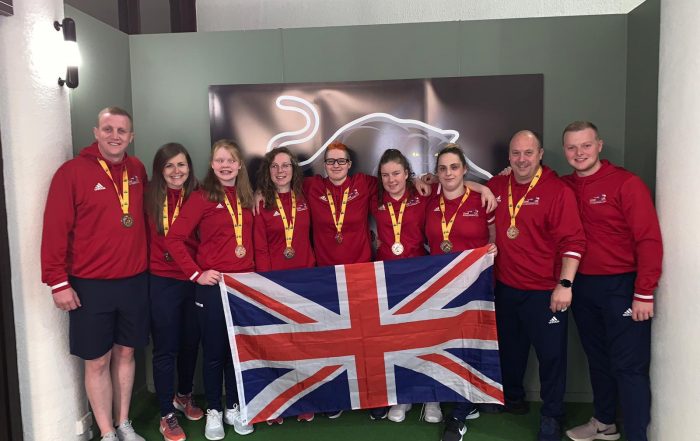 Group photo of GB Women under 19s with their bronze medals and holding the Union Flag