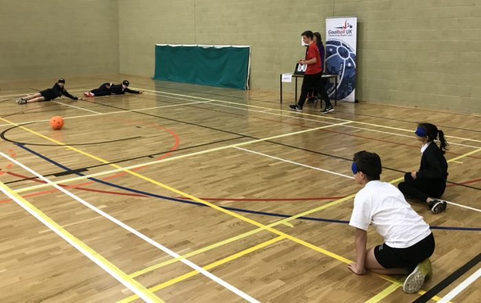 Action shot, with players on court, at a school goalball competition.