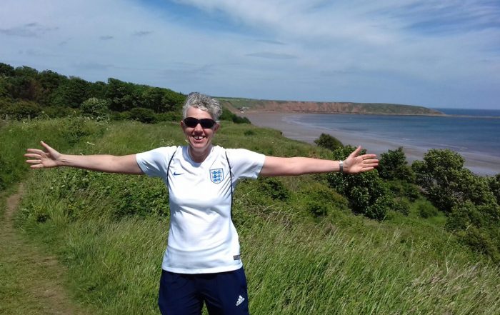 Kathryn smiling, with the cliffs of Filey (North Yorkshire) in the background