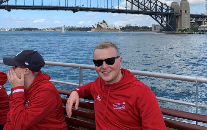 Tom Dobson smiling, with the Sydney Harbour Bridge and Opera House in the background
