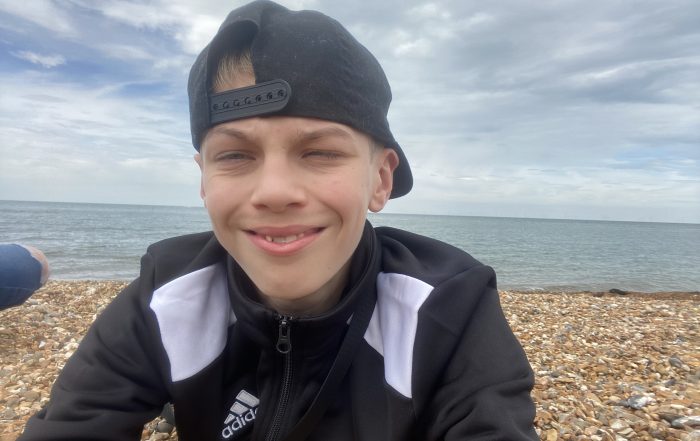 Bobbie-Jack on a beach, smiling and looking at the camera.