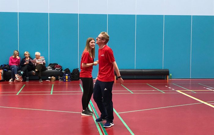 Imogen in the centre of the goalball court at the beginning of a game, shaking hands with her co-official