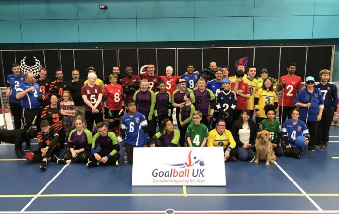 Group photo of the goalball family behind a Goalball UK banner
