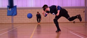 Image of a Winchester Goalball Club player throwing a ball at an elite tournament. Dina Murdie watching on.