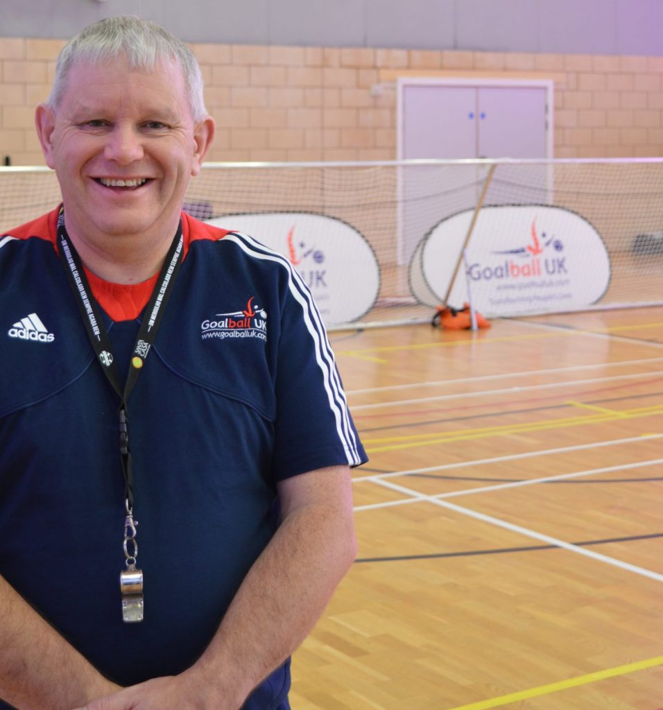 Smiley photo of Robert Avery in front of a goalball goal at The Factory Community Centre, Birmingham