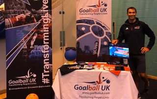 View of a standard Goalball UK stand at a university volunteering fair, with Steve Cox standing and smiling at the side.