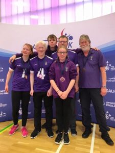Image shows Charlie stood with his Scarborough teammates in front of a Goalball UK banner