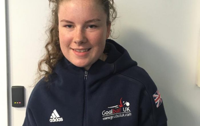 Image shows Megan stood smiling at the camera, wearing her Goalball UK jacket!