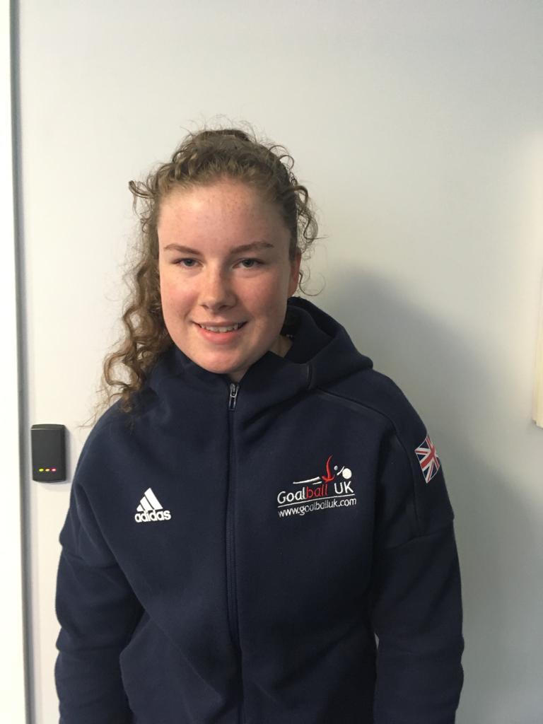 Image shows Megan stood smiling at the camera, wearing her Goalball UK jacket!