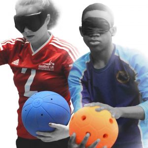 A Great Britain women's player holding a goalball, stood next to a young male player preparing to shoot an orange jingle ball.