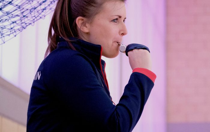 A female referee, refereeing a game of goalball