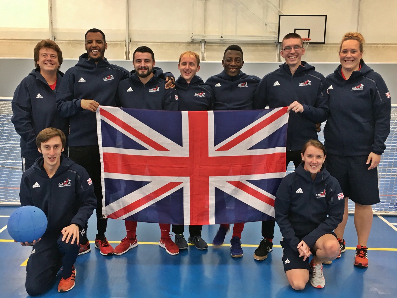 Image shows Faye (bottom right) with the 2017 GB Men's team holding the Union Jack flag
