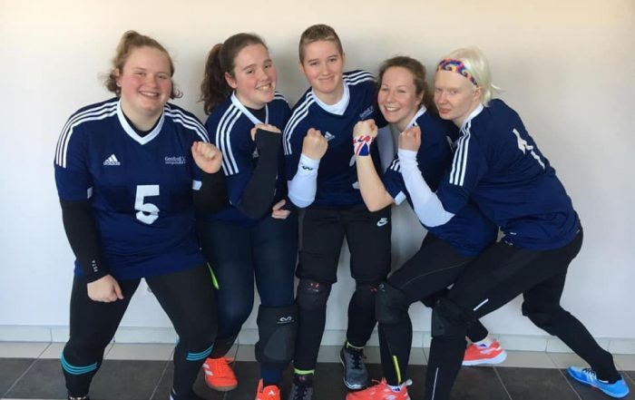 GB Women's Squad stood together closely with smiles and closed fists to the air!