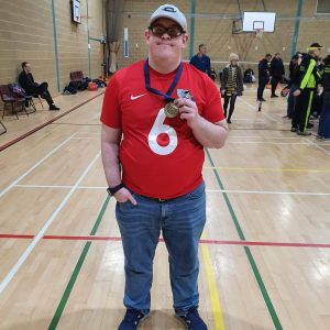 Image shows Joe Scott stood smiling at the camera, proudly holding his medal after a tournament!