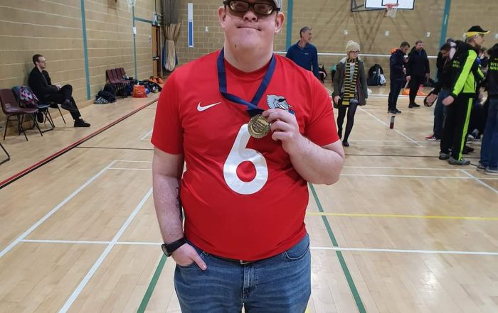 Image shows Joe Scott stood smiling at the camera, proudly holding his medal after a tournament!