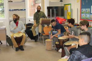 Young people and their parents taking part in a Drumming workshop at a Family Day