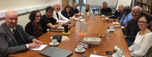 Sight Loss Council members sat around a table, all smiling, at a Sight Loss Council meeting