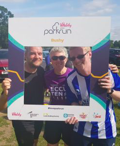 Phil Green, Kathryn Fielding and Stephen Newey standing together holding a park run sign.