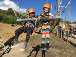 2 young girls with helmets and harnesses on taking part in an outdoor activity