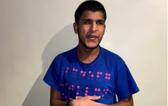 Yusuf Huraira's Youth Forum photo. In the photo Yusuf is wearing a dark blue top with braille printed onto it.