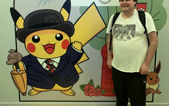 Image shows Graham Bowe stood next to a Pikachu graphic at the pokemon centre
