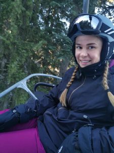 Josie Hewson pictured on a ski lift whilst wearing skiing gear including a thick black coat and purple ski trousers!