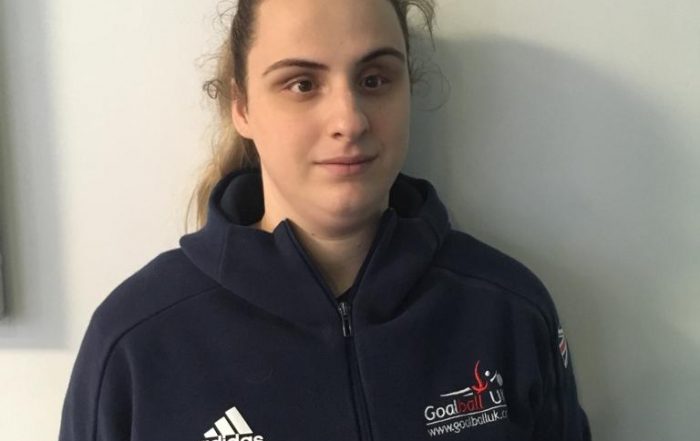 An image of Nansi stood looking at the camera, wearing a Goalball UK jacket
