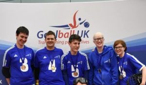 A group photo of an Intermediate team of Cambridge Dons in front of a Goalball UK banner.