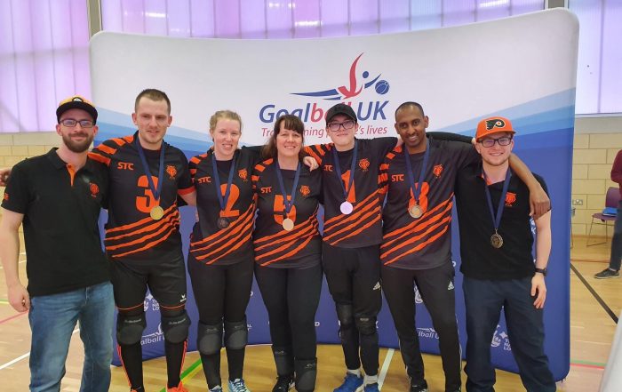 Fen Tigers group photo at a tournament in their orange and black playing jerseys. Medal are around their necks with pride!