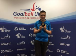 Charlie Brown stood with a small trophy whilst wearing a Leeds United top.