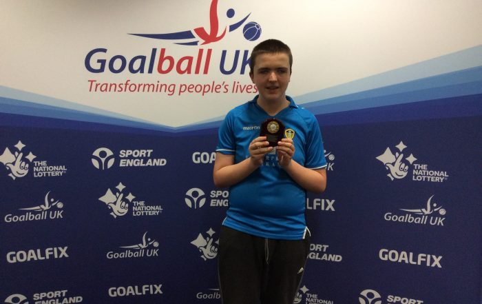 Charlie Brown stood with a small trophy whilst wearing a Leeds United top.