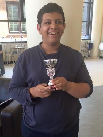 Khalil holding a silver trophy with a big cheesy smile on his face!
