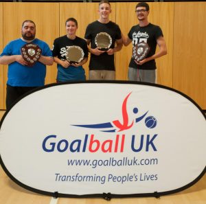 Matt Wooff stood in a past team photo and stood on the right side of the four players. They are all stood in front of a Goalball UK banner.
