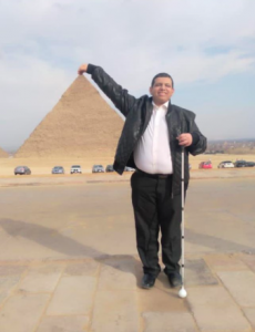 Khalil in front of a pyramid in Egypt! Khalil is doing a pinching action with the top of the pyramid in the background, impressive!