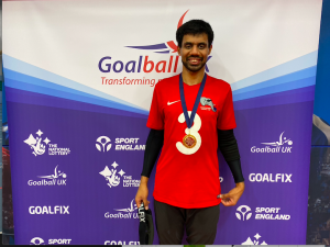Naqi Rizvi wearing player of the weekend medal in front of a banner.