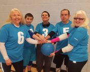 5 Glasgow goalball players standing all having one hand on a goalball!
