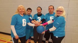 5 Glasgow goalball players standing all having one hand on a goalball!
