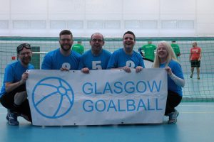 Glasgow goalball team standing in front of a goal holding a Glasgow goalball banner.