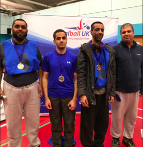 Riyaz Hazi stood in a group photo with his fellow Kirklees teammates in front of a Goalball UK banner.