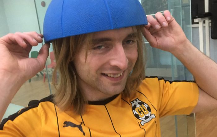 Warren Wilson wearing a Cambridge United FC shirt, wearing half of a goalball he split in half!